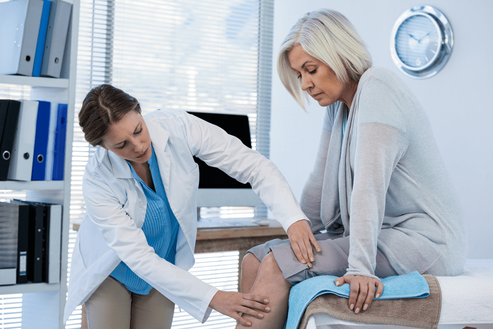 Лекарот испитува пациент со артроза на коленото зглоб